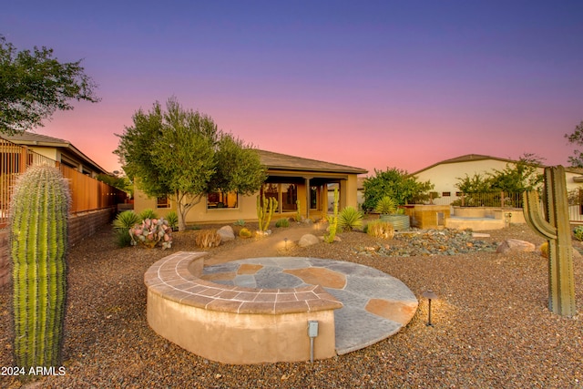 back house at dusk featuring a hot tub and a patio area