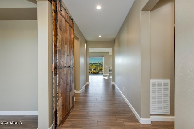 corridor with a barn door and dark wood-type flooring