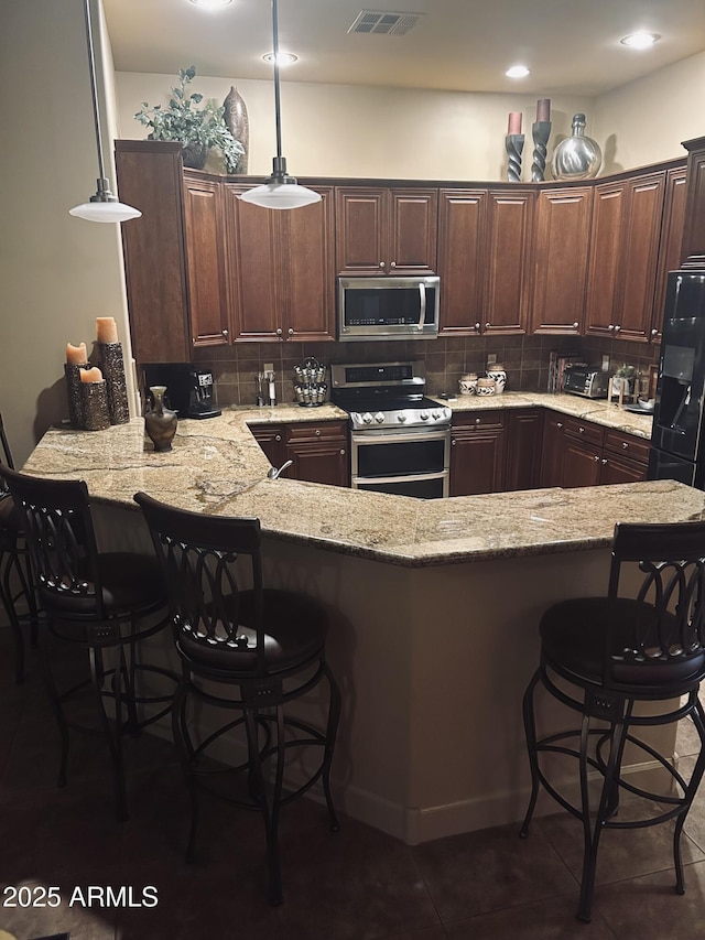 14000 N 94th St Unit 1077, Scottsdale, AZ 85260 - kitchen featuring stainless steel appliances, tasteful backsplash, a peninsula, and light stone countertops
