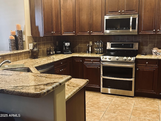 14000 N 94th St Unit 1077, Scottsdale, AZ 85260 - kitchen with stainless steel appliances, decorative backsplash, a peninsula, and light tile patterned floors