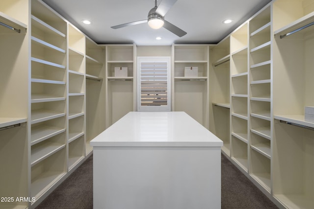 walk in closet with dark colored carpet and ceiling fan