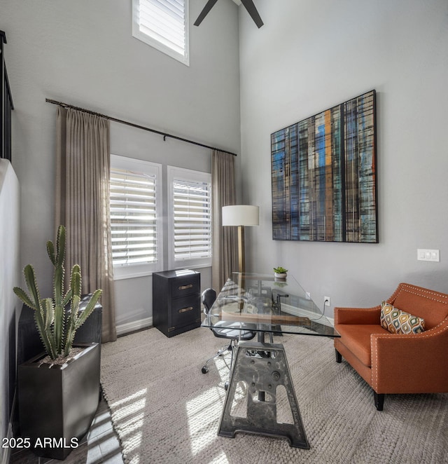 interior space featuring carpet floors, ceiling fan, and a towering ceiling