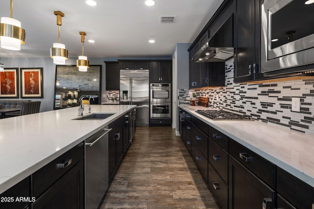 kitchen with pendant lighting, sink, dark hardwood / wood-style floors, built in appliances, and decorative backsplash