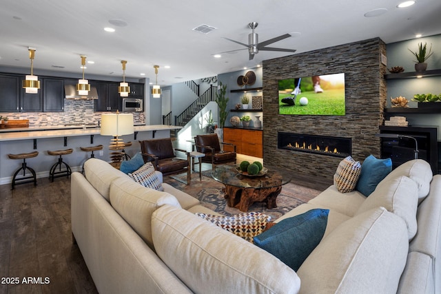 living room with dark wood-type flooring, ceiling fan, and a fireplace