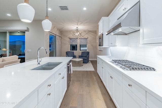 kitchen featuring white cabinets, sink, light hardwood / wood-style flooring, decorative light fixtures, and stainless steel appliances