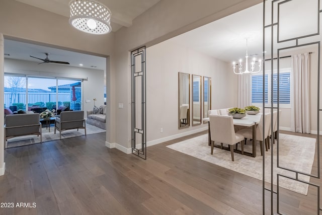 dining area with ceiling fan with notable chandelier and dark wood-type flooring