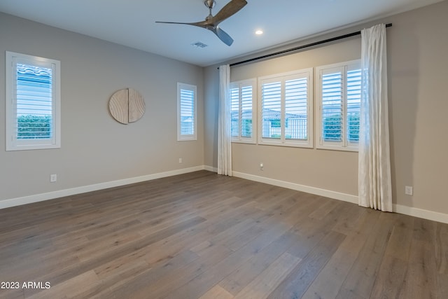 unfurnished room featuring hardwood / wood-style floors, ceiling fan, and a healthy amount of sunlight