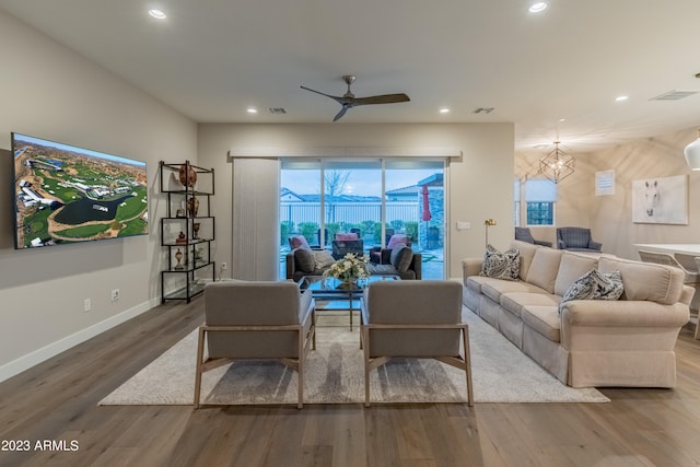 living room with hardwood / wood-style floors and ceiling fan with notable chandelier