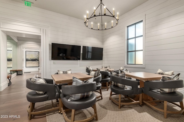 dining room with a chandelier, light hardwood / wood-style floors, and wood walls