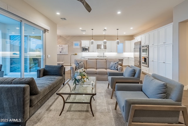 living room featuring ceiling fan, light hardwood / wood-style floors, and sink