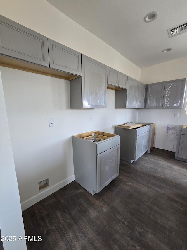 kitchen with dark wood-style floors, visible vents, gray cabinets, and baseboards