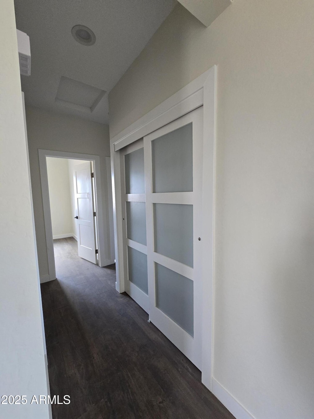 hallway featuring attic access, dark wood-type flooring, and baseboards