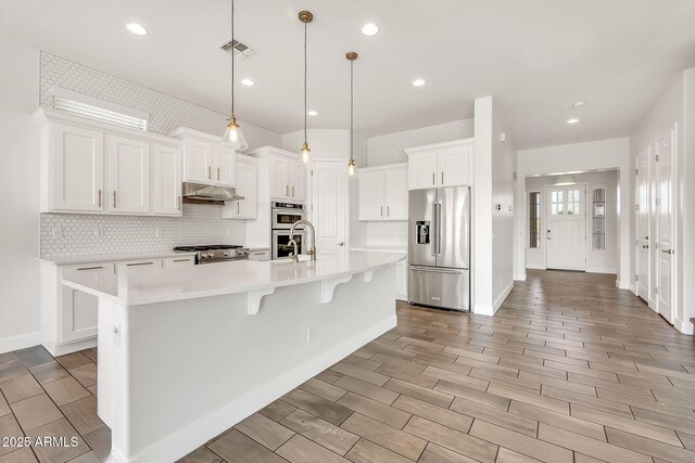9017 E June Cir, Mesa, AZ 85207 - kitchen with premium appliances, under cabinet range hood, backsplash, light countertops, and white cabinetry