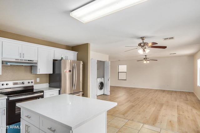 kitchen featuring under cabinet range hood, washer and dryer, range with electric stovetop, freestanding refrigerator, and light countertops