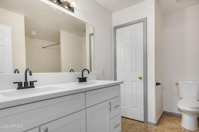 bathroom with tile patterned flooring, double vanity, toilet, and a sink