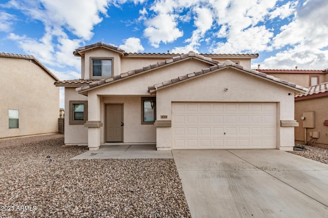 mediterranean / spanish house with a tile roof, stucco siding, an attached garage, and concrete driveway