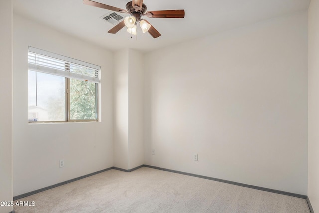 carpeted spare room featuring visible vents, ceiling fan, and baseboards