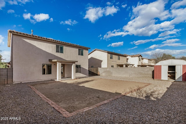 rear view of property featuring a patio, an outbuilding, a fenced backyard, stucco siding, and a storage shed