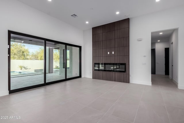 unfurnished living room featuring a large fireplace, a towering ceiling, and light tile patterned floors