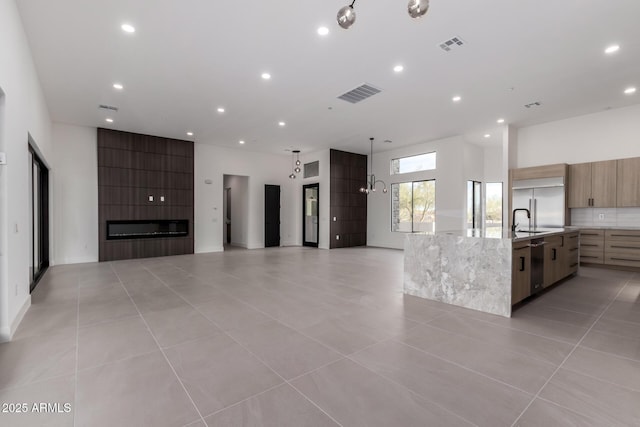 kitchen featuring sink, a large fireplace, stainless steel appliances, a large island, and backsplash