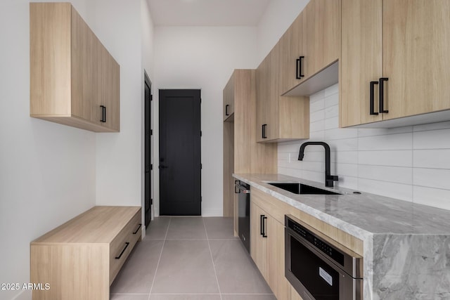 kitchen with light brown cabinetry, sink, and dishwasher