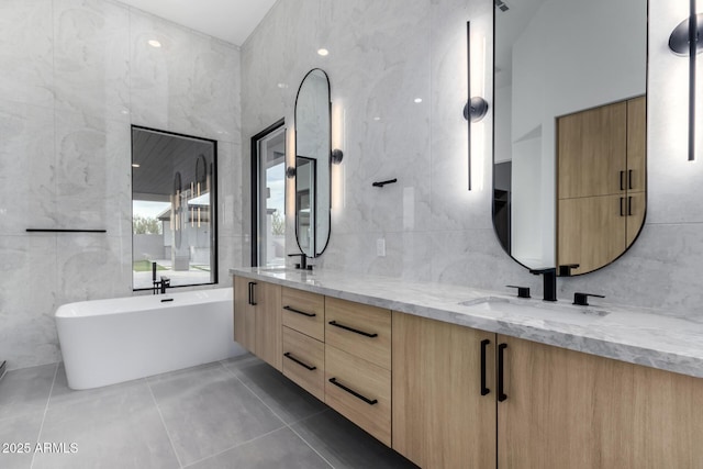 bathroom with vanity, tile walls, tile patterned floors, and a bathtub