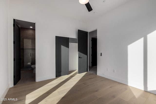 unfurnished bedroom featuring ensuite bathroom, ceiling fan, and light wood-type flooring