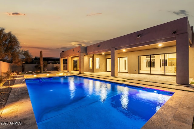 pool at dusk featuring a patio and pool water feature