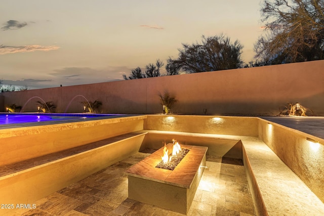 patio terrace at dusk featuring a fire pit