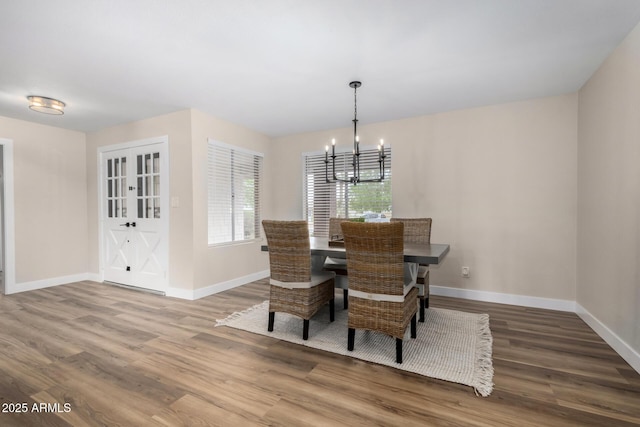 dining area featuring a chandelier, baseboards, and wood finished floors