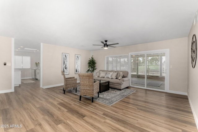 living room with baseboards, a ceiling fan, and light wood finished floors