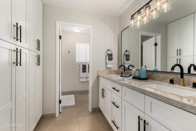 full bath with double vanity, a sink, tile patterned flooring, and baseboards