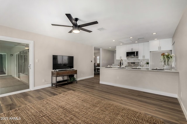 kitchen with dark wood finished floors, a ceiling fan, white cabinets, appliances with stainless steel finishes, and open floor plan