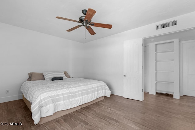 bedroom featuring visible vents, a ceiling fan, baseboards, and wood finished floors
