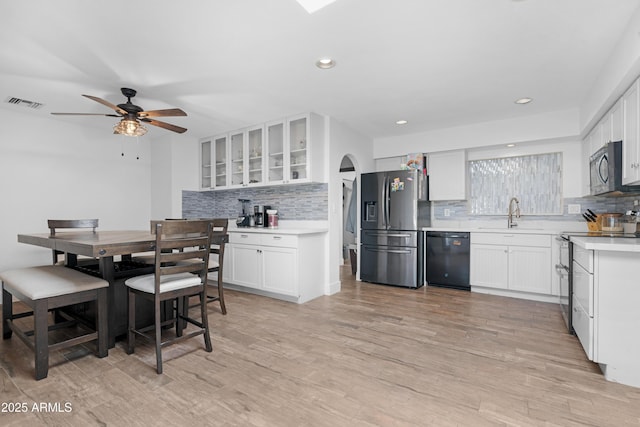 kitchen featuring appliances with stainless steel finishes, a sink, a ceiling fan, decorative backsplash, and visible vents