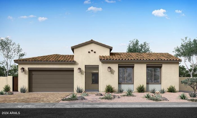 mediterranean / spanish house with a tiled roof, decorative driveway, a garage, and stucco siding