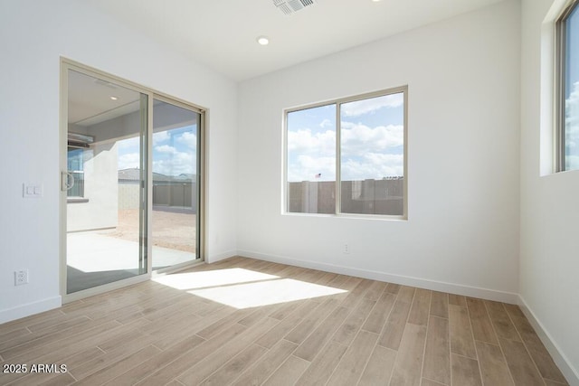 unfurnished room with visible vents, light wood-style flooring, and baseboards