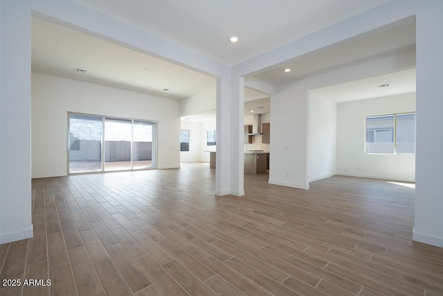 unfurnished living room featuring recessed lighting, baseboards, and wood finished floors