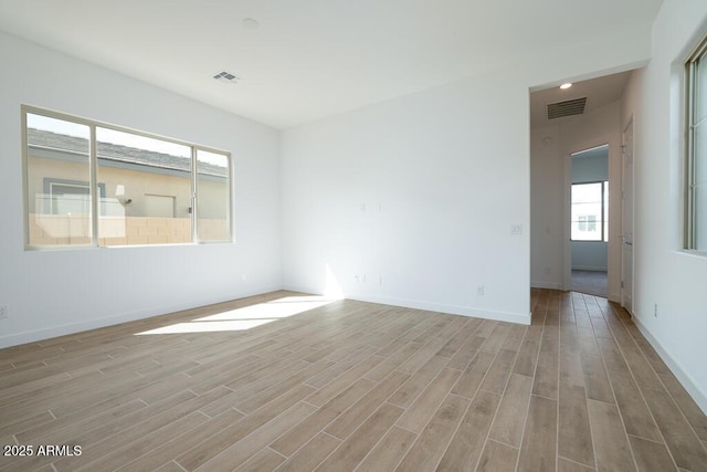 spare room featuring visible vents, light wood-style flooring, and baseboards