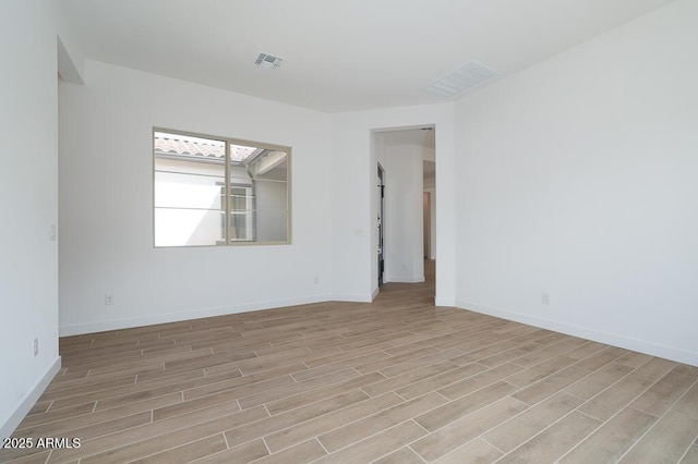 spare room featuring baseboards, visible vents, and wood tiled floor