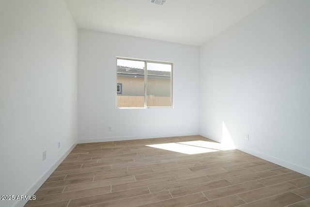 spare room featuring visible vents, baseboards, and wood finish floors