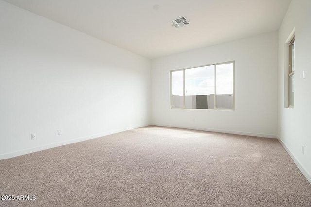 spare room featuring baseboards, light carpet, and visible vents