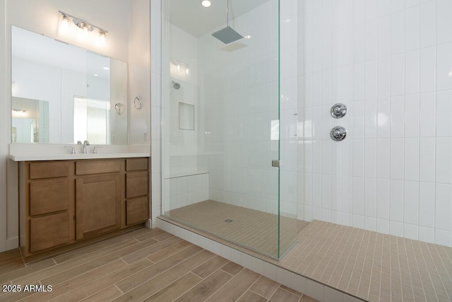 full bathroom with wood finish floors, tiled shower, and vanity