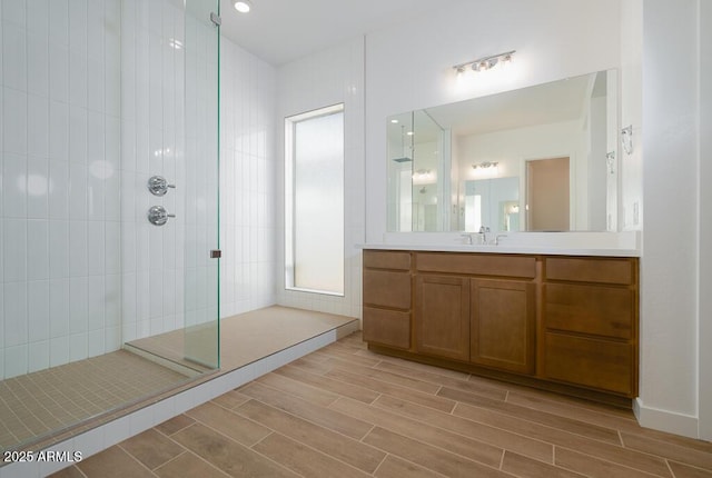 full bath with vanity, wood tiled floor, and a tile shower