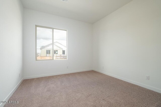 spare room with baseboards and light carpet