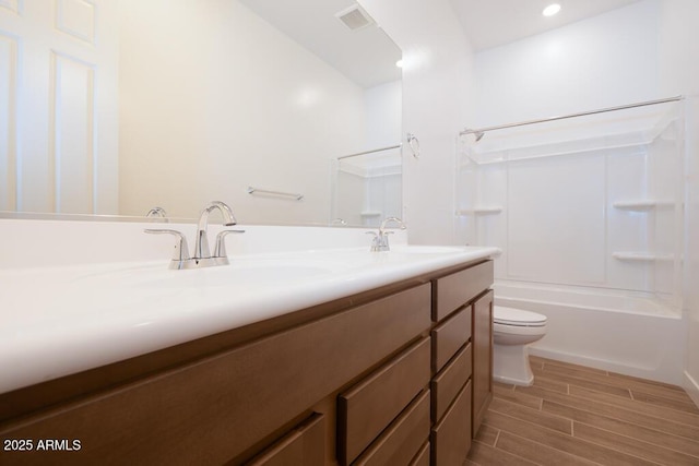 bathroom featuring visible vents, toilet, a sink, double vanity, and wood tiled floor