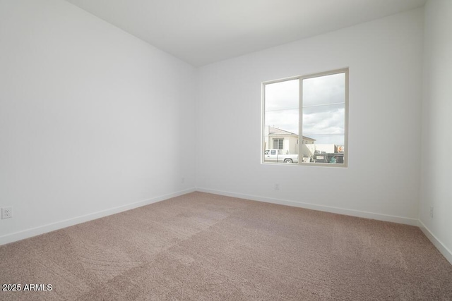 unfurnished room with baseboards and light colored carpet