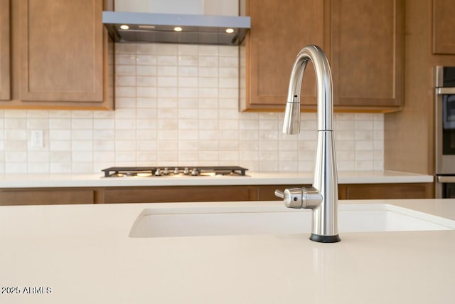 details with backsplash, extractor fan, light countertops, brown cabinetry, and a sink