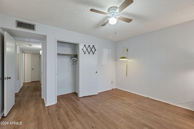 unfurnished bedroom featuring visible vents, ceiling fan, a textured ceiling, light wood-style floors, and a closet