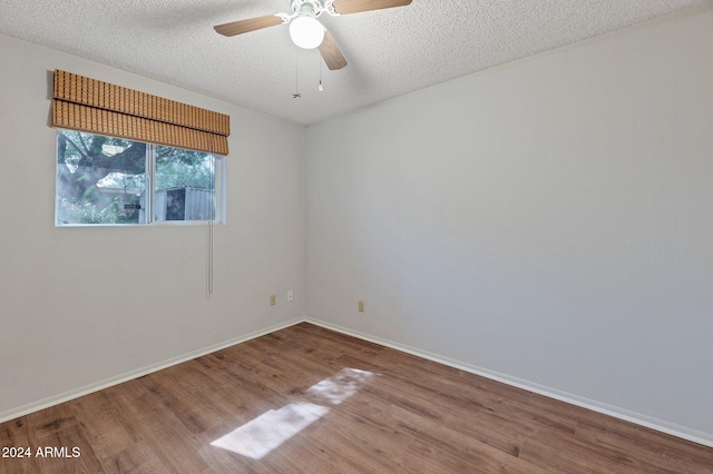 spare room featuring a textured ceiling, wood finished floors, a ceiling fan, and baseboards